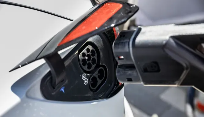 Nahaufnahme eines geöffneten DC-Ladeanschlusses an einem Elektroauto, ein Schnellladestecker wird abgezogen, lSchritt 3 der Ladeanleitung für DC-Laden.