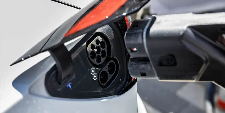 Nahaufnahme eines geöffneten DC-Ladeanschlusses an einem Elektroauto, ein Schnellladestecker wird abgezogen, lSchritt 3 der Ladeanleitung für DC-Laden.